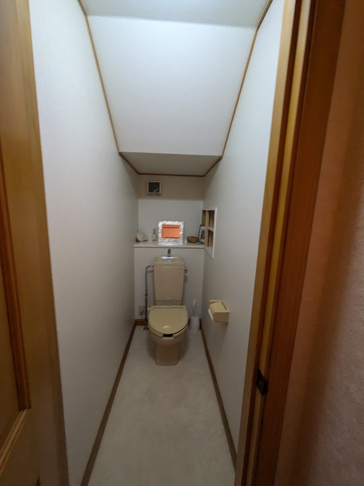リフォーム前のトイレ。便器の上に収納棚があり、右手の壁にニッチがある
