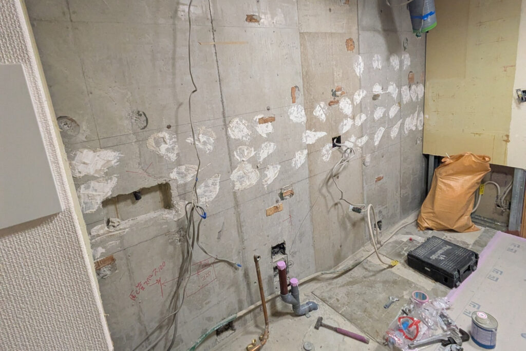 解体後のキッチン。下地まで戻したコンクリートの壁に、新しい給水管と排水管を立ち上げている