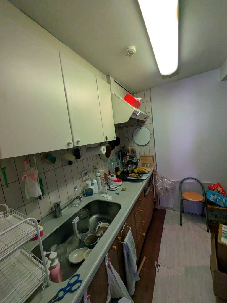 工事前の台所。居間・食堂と壁で仕切られた独立型で、吊戸棚と作業台が細長く並ぶ