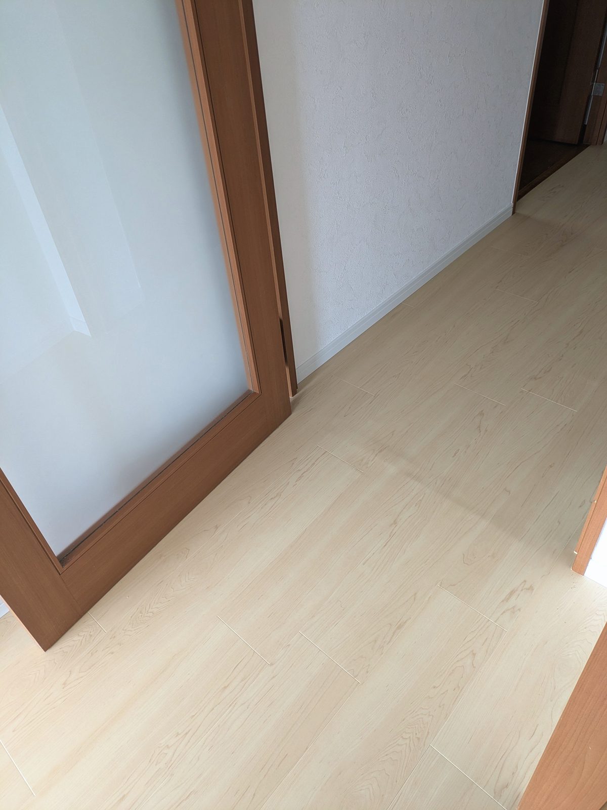 新しいフロアタイルと、濃い色の既存建具枠との取り合いを写した床のディテール