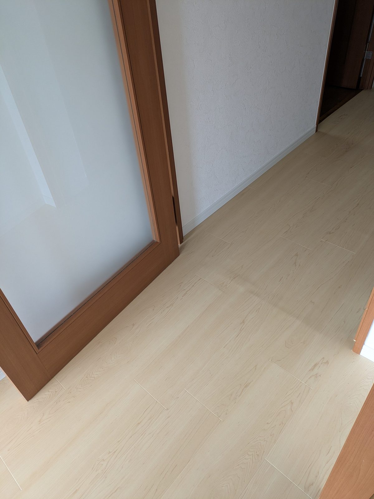新しいフロアタイルと、濃い色の既存建具枠との取り合いを写した床のディテール