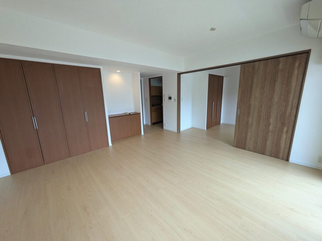 新宿区のマンション。明るいメイプル柄の床のリビング・ダイニング。右に3枚連動引き戸、左は既存の大型物入