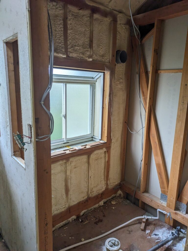 杉並区の戸建て。浴室を解体した状態。出窓は残したまま、柱と間柱、既存の断熱材、換気ダクトの開口が見えている