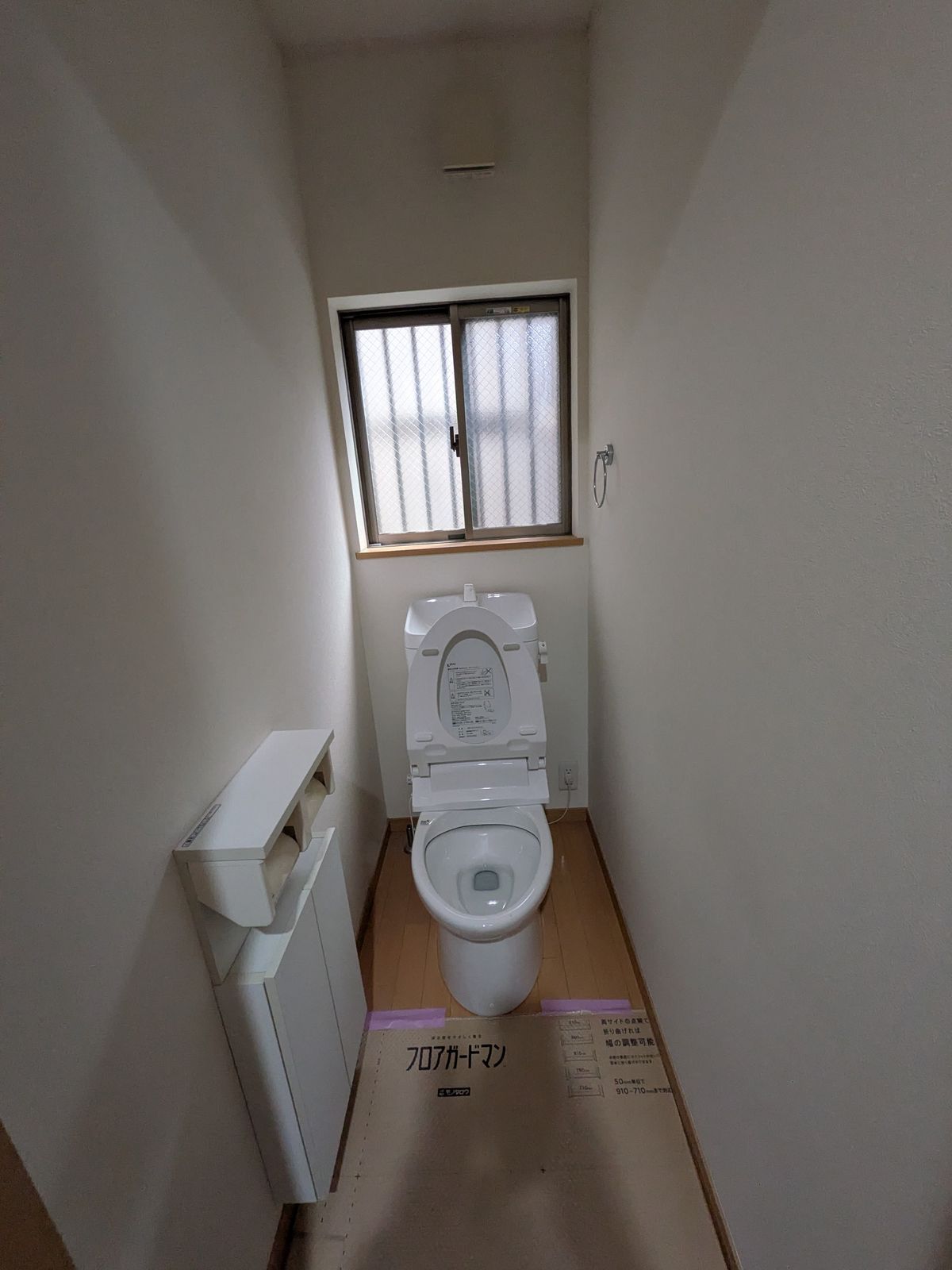 リフォーム前の1階トイレ。窓の下に便器があり、左に収納がある