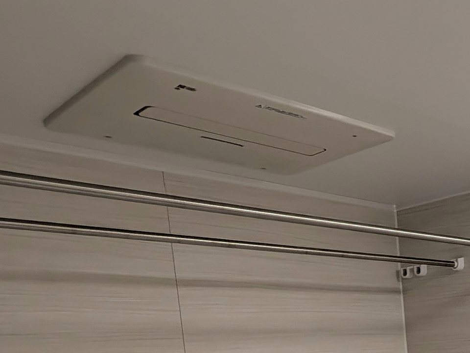 天井の温水式浴室暖房換気乾燥機と、その下に並ぶ2本のランドリーパイプ